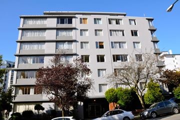 Vancouver apartment for rent - A grey apartment building with cars parked in front.