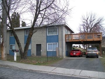 Pullman apartment for rent - A carport with a red car and a grey car parked in front of a two-story building.