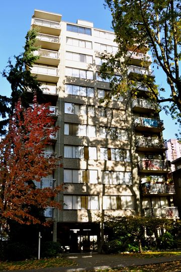 Vancouver apartment for rent - A tall building with balconies and a tree with red leaves in front.