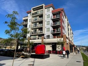 Kelowna apartment for rent - A large red sculpture sits in front of a modern apartment building.