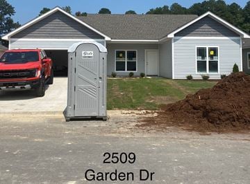 Benton house for rent - A red truck is parked in front of a house with a porta potty in the driveway.