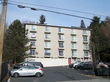 Pullman apartment for rent - A silver car is parked in front of a building with a white sign on the wall.