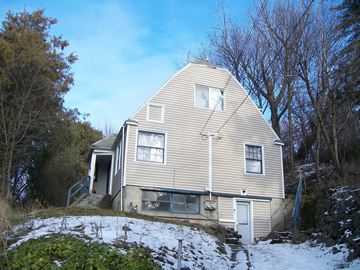 Pullman apartment for rent - A house with a sloped roof and a white door is surrounded by trees.