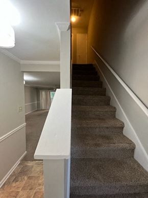 Garner apartment for rent - a hallway with stairs and a white railing and a door