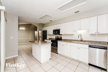 Palm Coast house for rent - a large kitchen with white cabinets and black appliances
