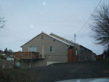 Pullman apartment for rent - A house with a green door is surrounded by a fence and trees.