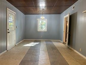 Pensacola house for rent - A room with a wooden ceiling and a tiled floor.