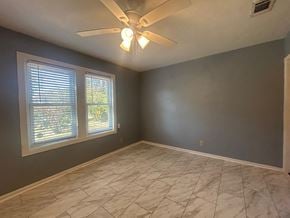 Pensacola house for rent - A room with a ceiling fan and a window with blinds.