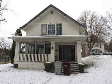 Pullman apartment for rent - A small white house with a porch and a trash can in front.