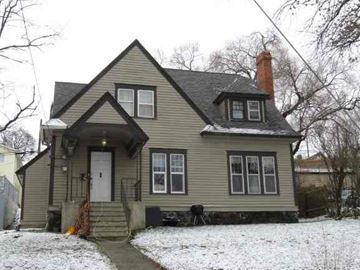 Pullman apartment for rent - A house with a grey siding and a white door is surrounded by snow.