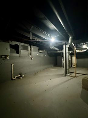 Louisville house for rent - a dark basement room with pipes and a light on the ceiling