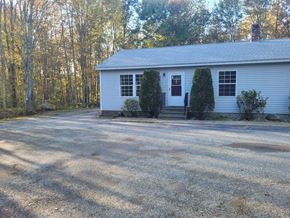 Gray apartment for rent - A white house with a gravel driveway in front.
