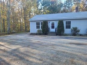 Gray apartment for rent - A white house with a gravel driveway in front.