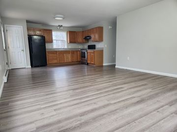 Gray apartment for rent - A kitchen with wooden cabinets and a black refrigerator.