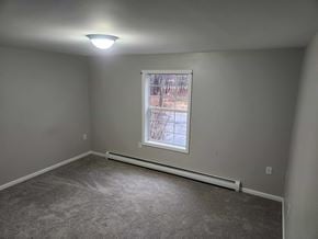 Gray apartment for rent - A room with a window and a carpeted floor.