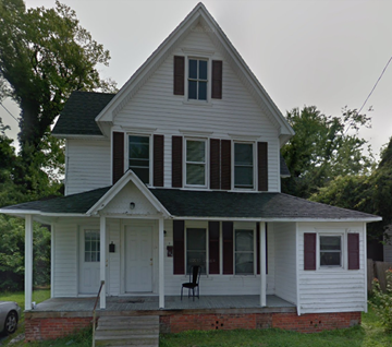 Pocomoke apartment for rent - A white house with a black roof and a red brick base.