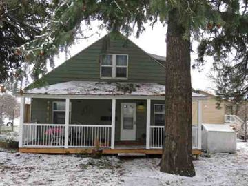 Pullman apartment for rent - A green house with a porch and a tree in front.