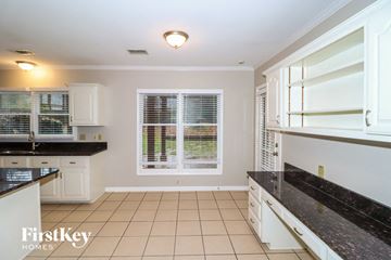 Memphis house for rent - a kitchen with white cabinets and black counter tops and a window