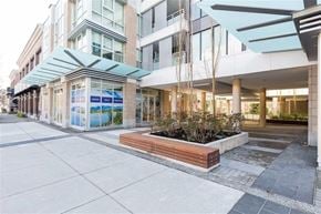 North Vancouver apartment for rent - A modern building with a glass facade and a wooden planter in front.