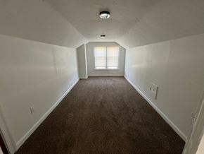 Lakewood apartment for rent - A long, empty hallway with a carpeted floor and a window at the end.