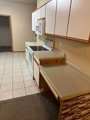 Fargo apartment for rent - A kitchen with white cabinets and a countertop with a sink and toaster oven.