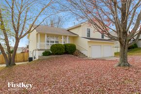 Kansas City house for rent - a yellow house with a yard with red leaves on the ground