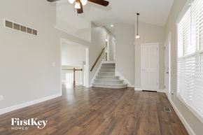 Kansas City house for rent - an empty living room with a staircase and a ceiling fan
