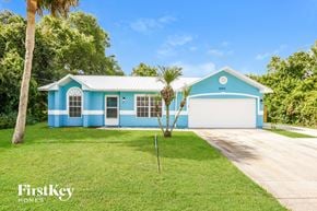 Cocoa house for rent - A blue and white house with a palm tree in front.
