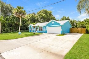 Cocoa house for rent - A blue house with a white garage door and a driveway in front.