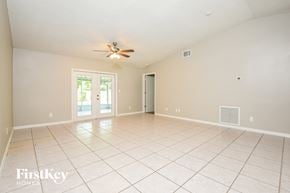 Cocoa house for rent - A spacious room with a ceiling fan and sliding glass doors.