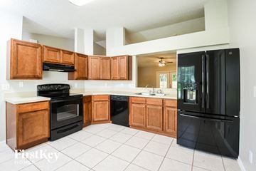 Cocoa house for rent - A kitchen with black appliances and wooden cabinets.