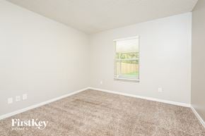 Cocoa house for rent - A room with a carpeted floor and a window showing a view of a lawn and trees.