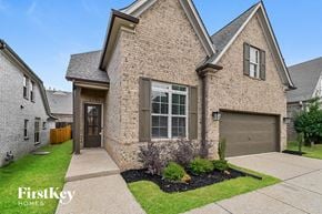 Cordova house for rent - A brick house with a garage door and a small garden in front.