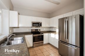 Tucson house for rent - a kitchen with white cabinets and stainless steel appliances