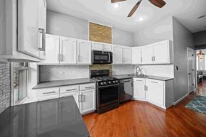 Chicago apartment for rent - A modern kitchen with white cabinets and a black stove top oven.