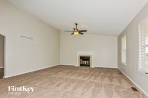 Troy house for rent - an empty living room with a ceiling fan and a fireplace