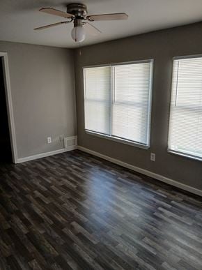 Louisville house for rent - an empty living room with wood floors and a ceiling fan