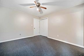 Jacksonville house for rent - an empty living room with a ceiling fan and white walls