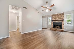 Jacksonville house for rent - an empty living room with a fireplace and a ceiling fan