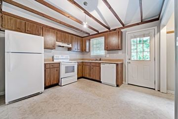 Jacksonville house for rent - A kitchen with wooden cabinets and a white refrigerator.