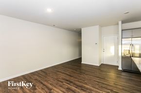 Huntersville house for rent - A spacious room with wooden flooring and white walls, with a door leading to another room.
