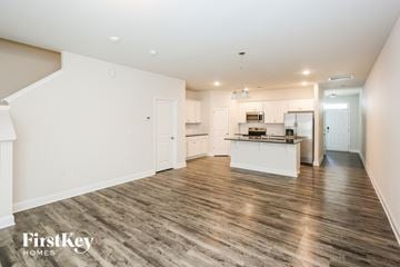 Concord house for rent - A spacious kitchen with white cabinets and a wooden floor.