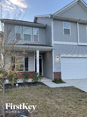 Charlotte house for rent - A grey house with a white garage door and a tree in front.