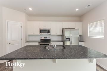 Charlotte house for rent - a kitchen with white cabinets and a granite counter top