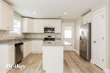Concord house for rent - A kitchen with white cabinets and a wooden floor.