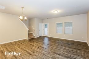 Concord house for rent - A spacious room with wooden flooring and a staircase leading to another level.