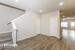 Lewisville house for rent - A spacious room with wooden floors and a staircase leading to the upper level.