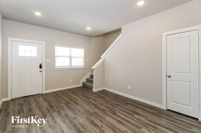 Lewisville house for rent - A spacious room with wooden flooring and a staircase leading to another level.
