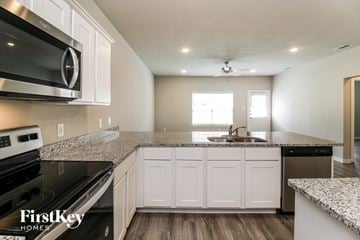 Lewisville house for rent - A kitchen with white cabinets and a granite countertop.