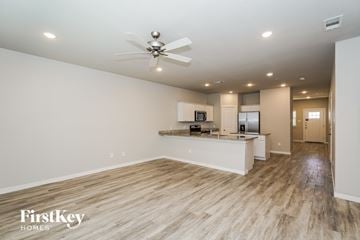 Lewisville house for rent - A spacious kitchen and living room with wooden floors and a ceiling fan.